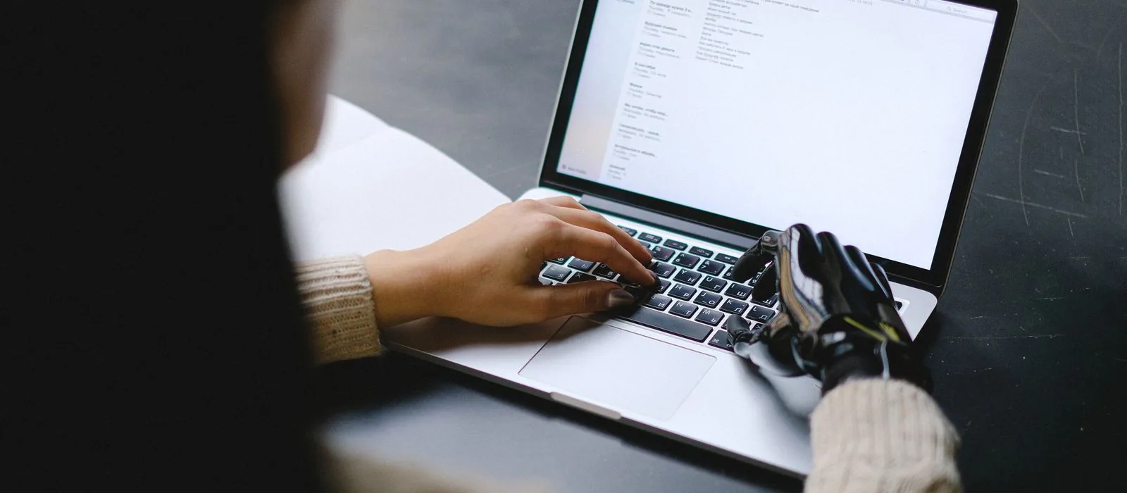 Iemand met een handprothese bedient een laptop